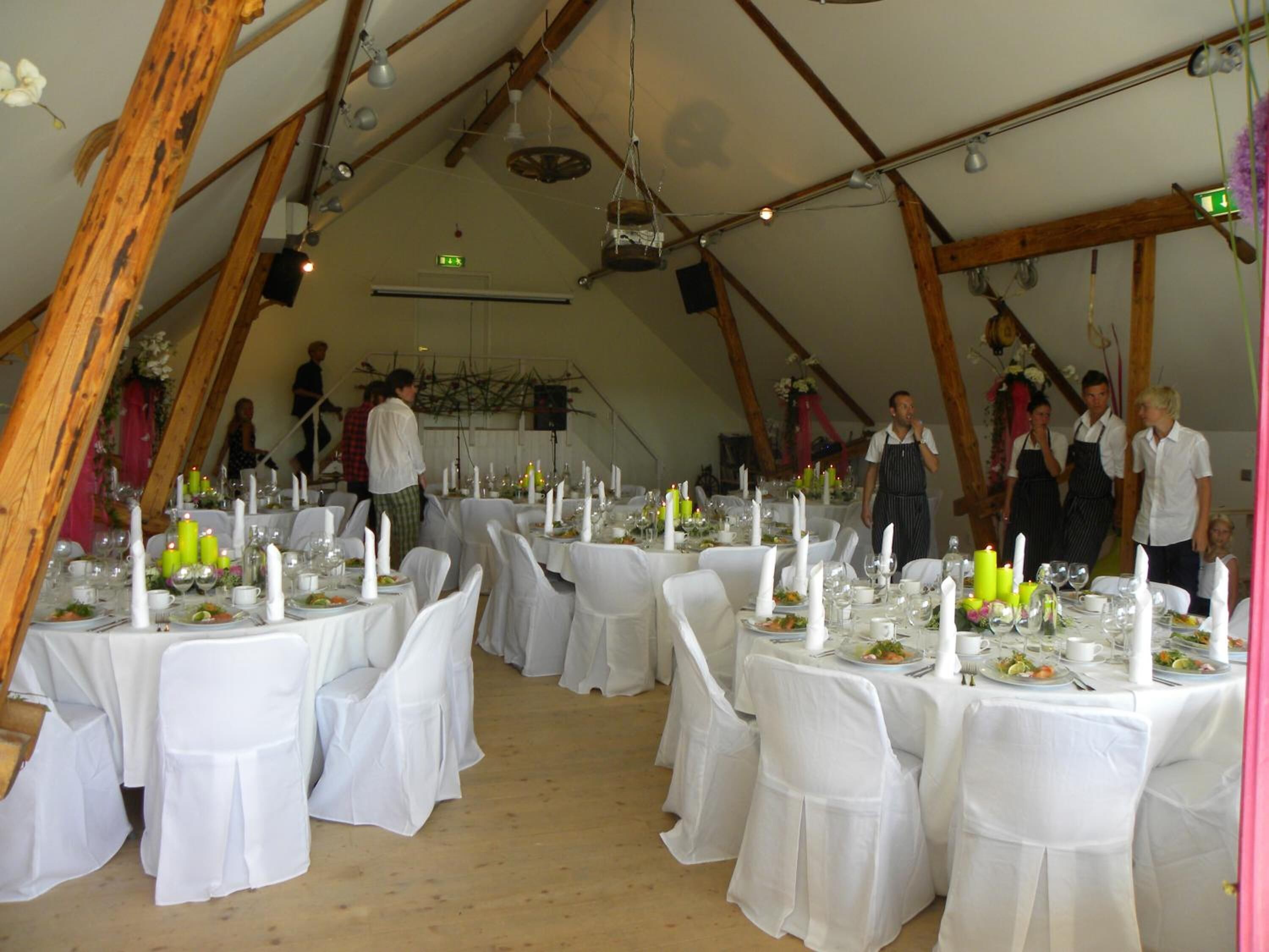 A tented dining area with round tables set for a meal, white tablecloths, and candles.