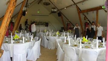 A tented dining area with round tables set for a meal, white tablecloths, and candles.