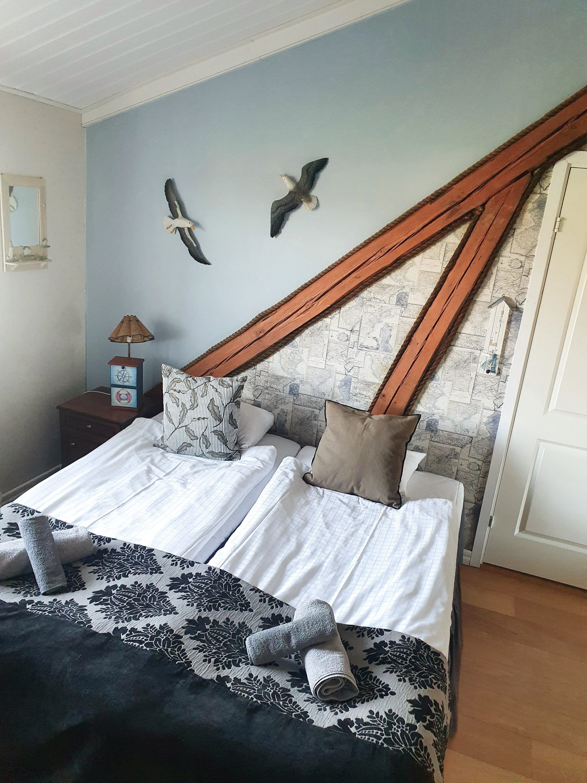 Una camera da letto con un letto, cuscini, un comodino, una lampada e decorazioni alle pareti.