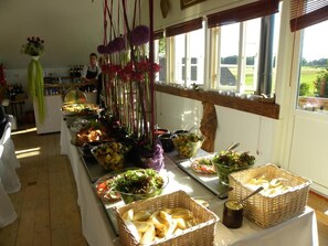 Una mesa de buffet con diversos alimentos y una persona sirviendo.