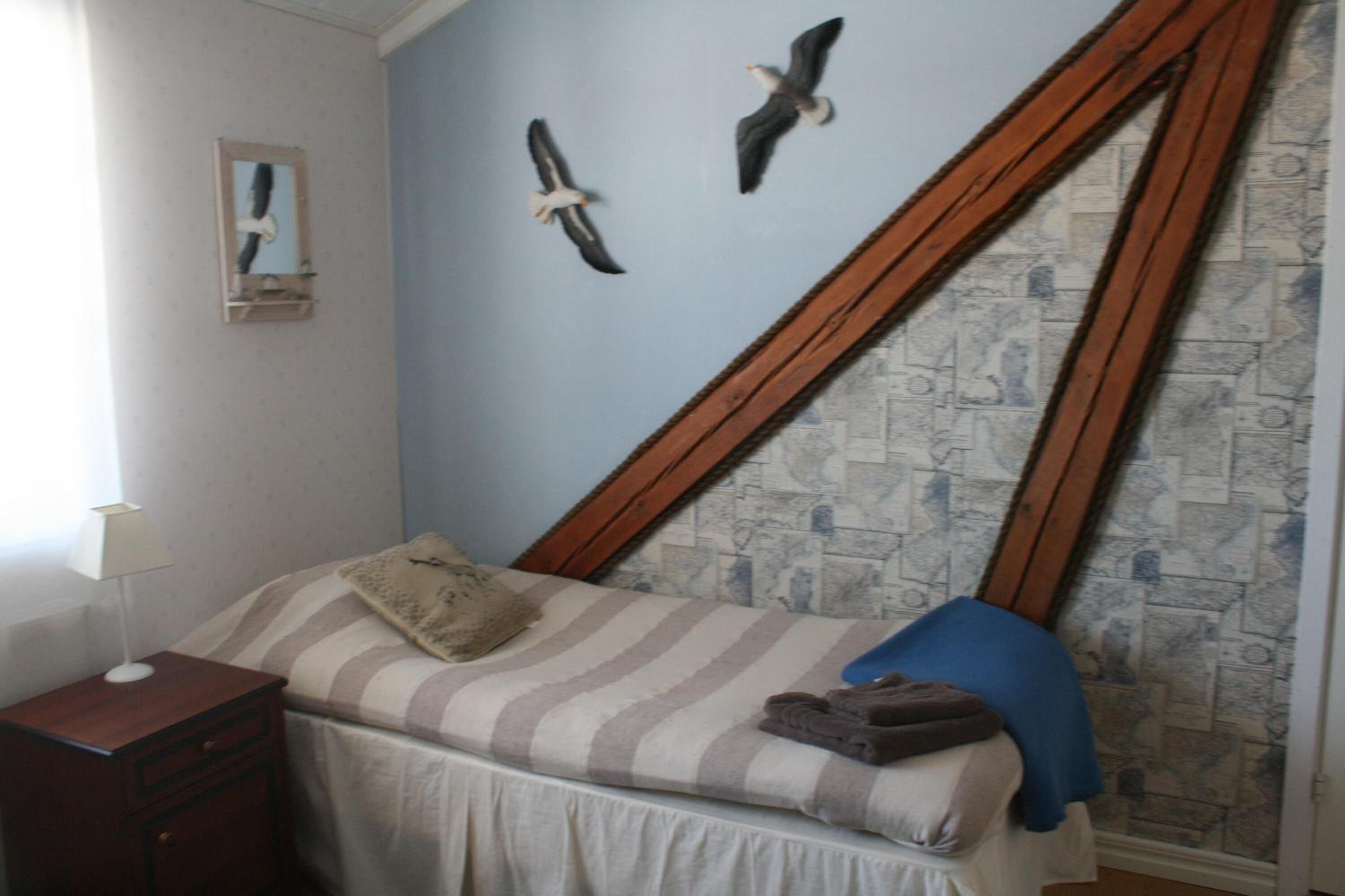 Quarto com cama, mesa de cabeceira, abajur e parede com design de mapa.