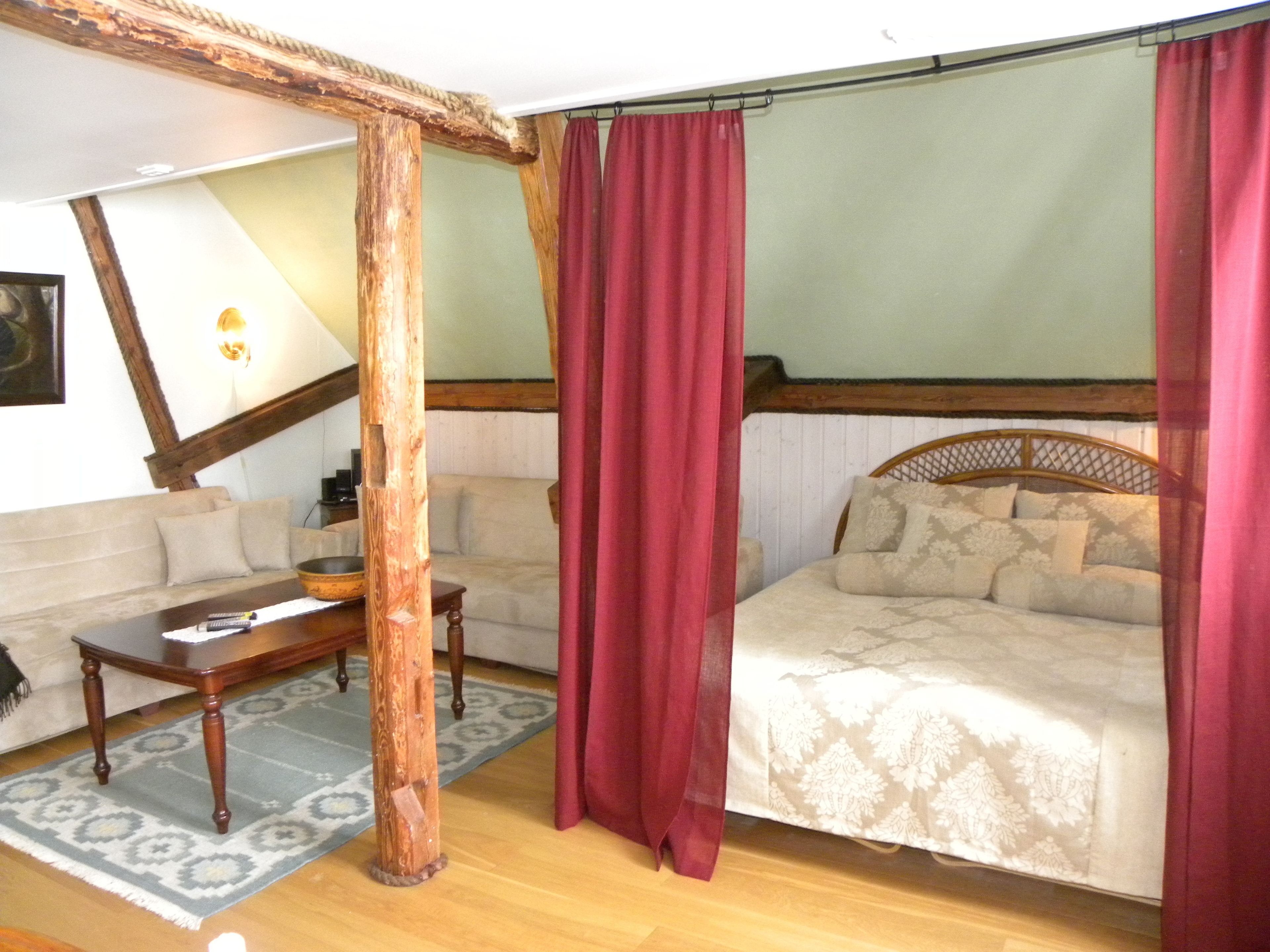 Une pièce comprenant un lit, un canapé, une table en bois et un grand miroir.