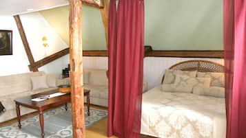 A room with a bed, a sofa, a wooden table, and a large mirror.