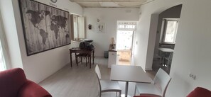 A dining area with a wooden table and chairs, a world map on the wall, and a view of the outside.