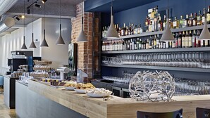 Un espace bar doté d’un comptoir en bois, d’étagères remplies de bouteilles d’alcool et d’une sculpture en verre décorative.