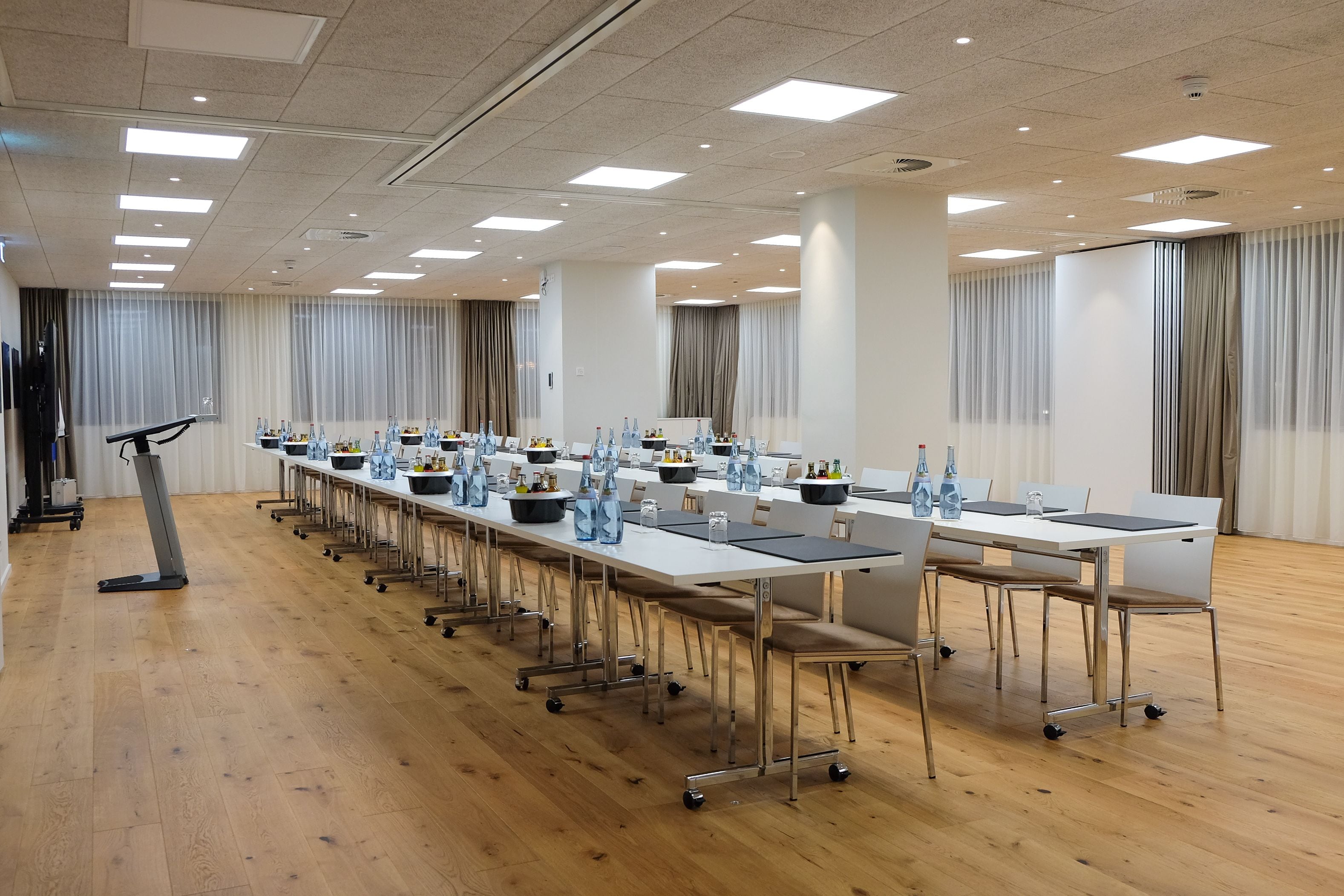 A conference room with long tables, chairs, and a treadmill.