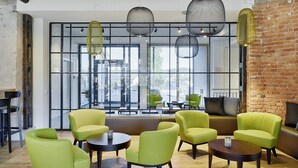 Un intérieur moderne avec des chaises vertes, un canapé et un mur en briques.