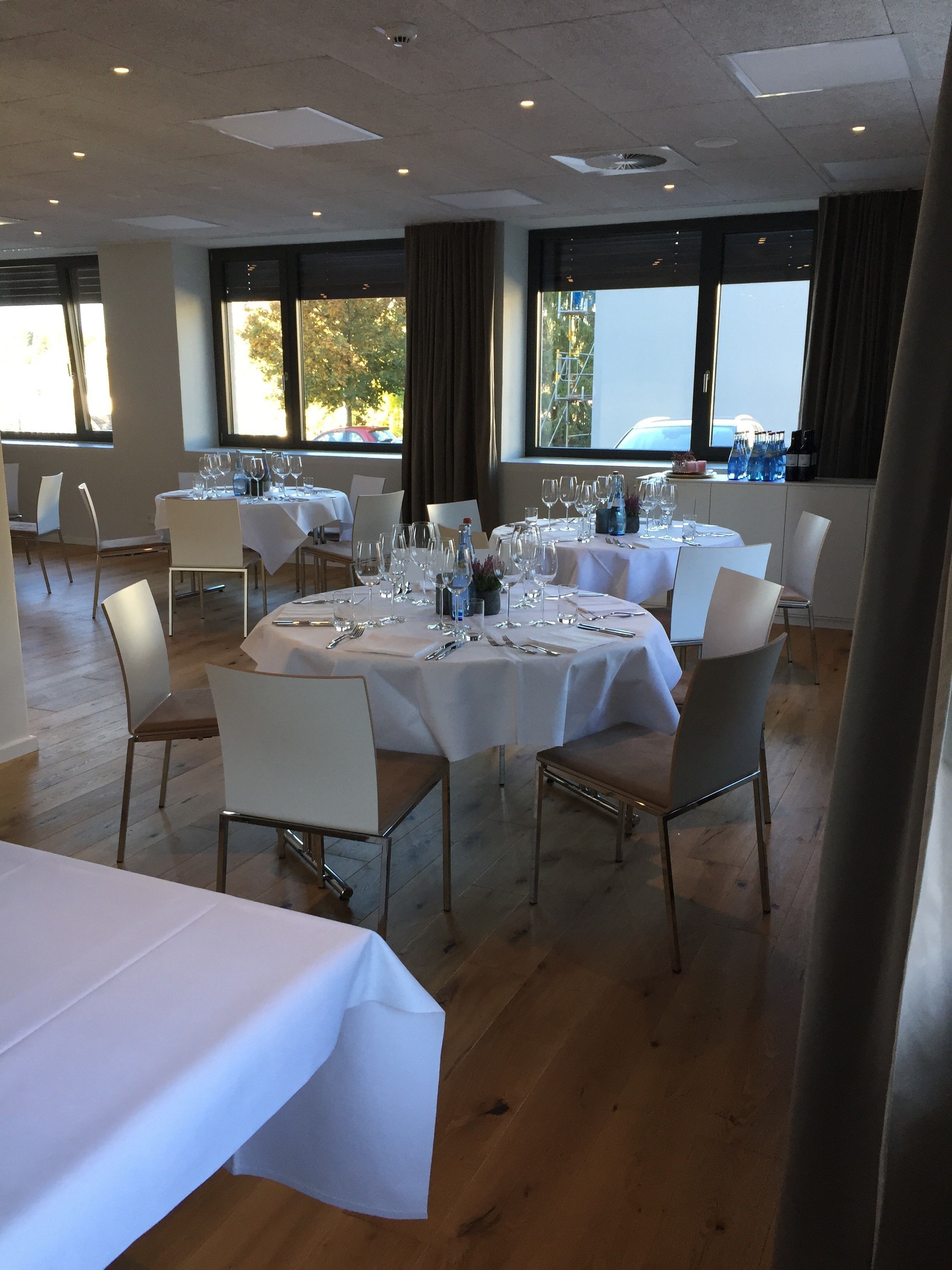 Un espace repas avec des tables rondes dressées pour le repas, des nappes blanches et des chaises.