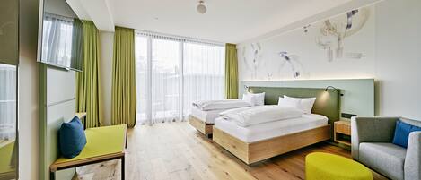 Une chambre d’hôtel avec un lit, un bureau, une chaise, un canapé et une grande fenêtre.