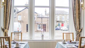 A dining area with two tables, chairs, and a window with a view of the street. - Hazeldene Guest House (Perth)