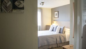 A bedroom with a bed, bedside table, and a wall-mounted lamp. - Hazeldene Guest House (Perth)