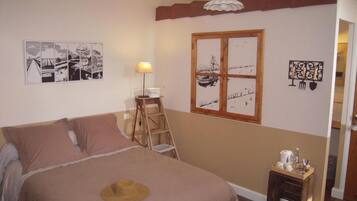Une chambre avec un lit, une échelle, une fenêtre et des œuvres d’art mural.