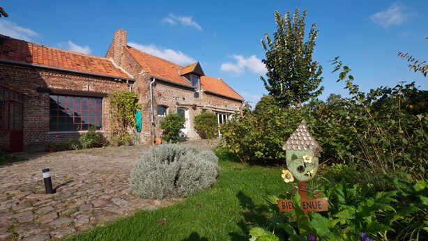 A traditional brick house with a tiled roof, a cobblestone pathway, and a garden with a birdhouse and a sign that reads "BIENVENUE". - B&B La Ferme de l'Ostrevent (Estrées)