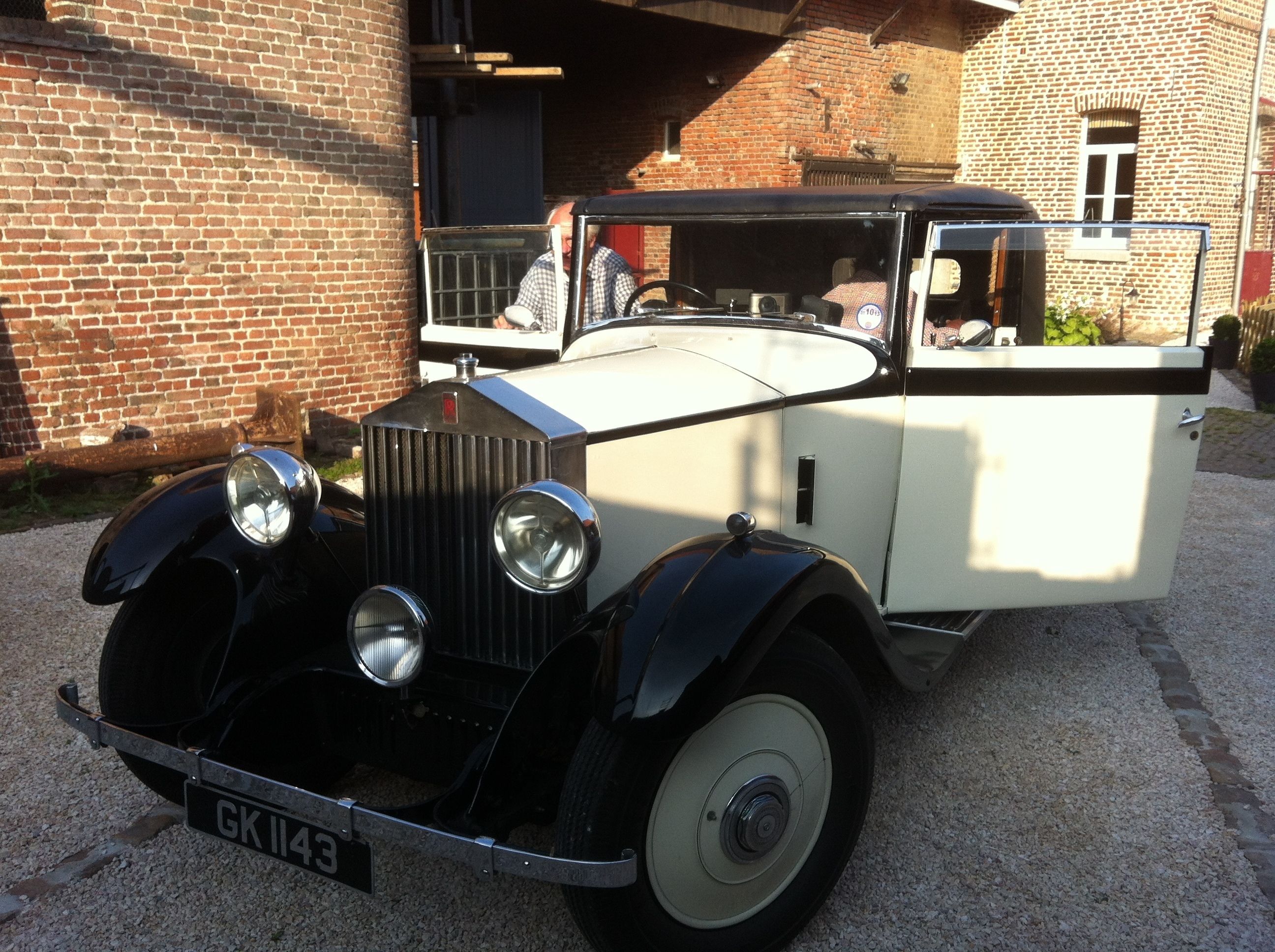 Ein Oldtimer vor einem Backsteinhaus.