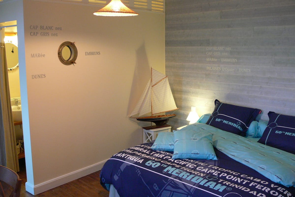 A bedroom with a bed, a sailboat decoration, and a wall with text.