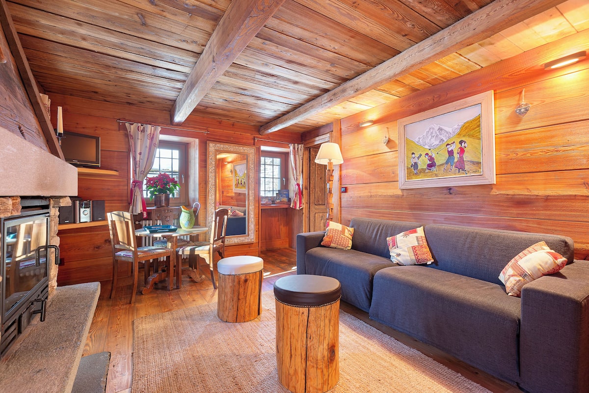 Een gezellig houten interieur met een bank, een eettafel en een open haard.