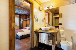 A wooden-framed bathroom with a large sink, a bidet, and a mirror. - Locanda 4 (Valtournenche)