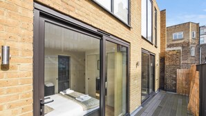 Quarto moderno com uma grande porta de correr de vidro, um deck de madeira e fachada de tijolos.