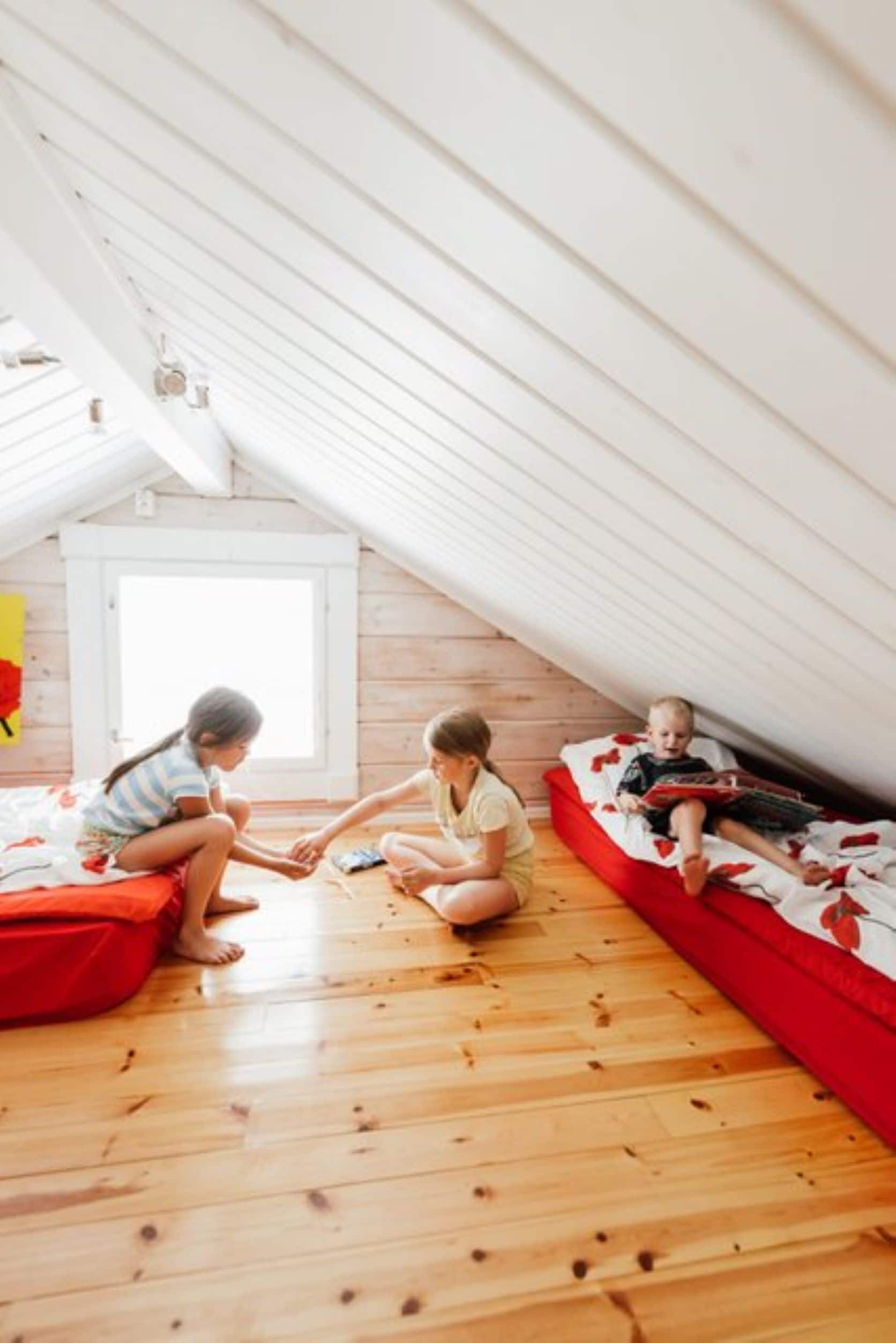 A room with a sloped ceiling, wooden flooring, and a window.