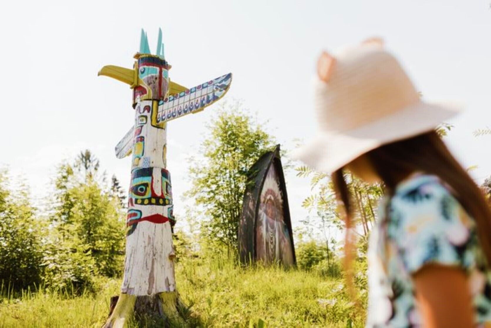 A totem pole and a wooden structure in a grassy area.