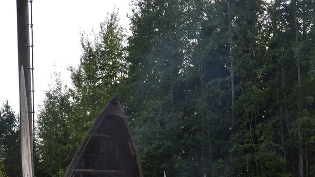 Tunnelmallinen ulkoilmalounausalue, jossa on nuotiopaikka, puiset penkit ja pöytä, jonka päällä on hedelmiä ja vihanneksia.
