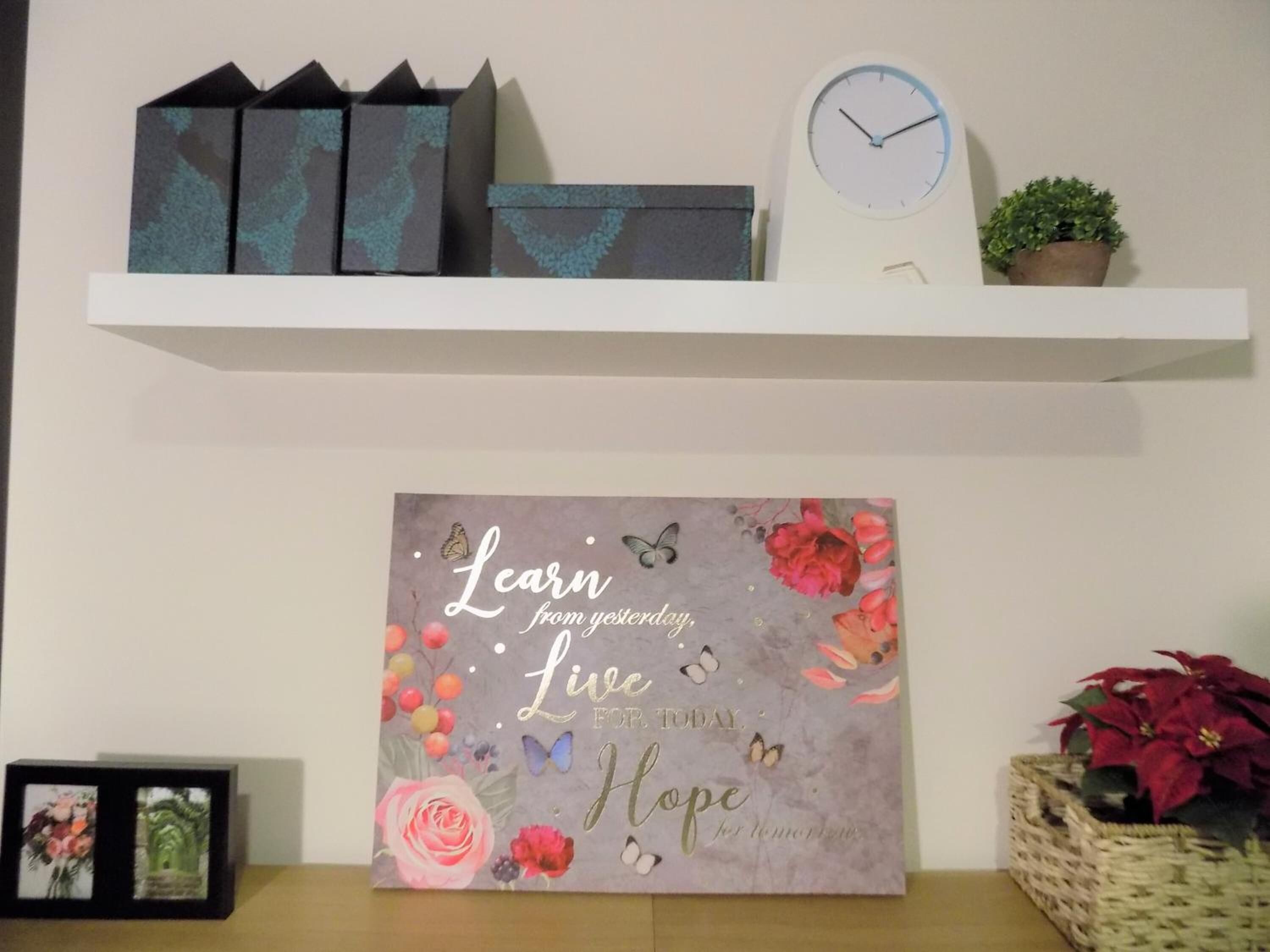 A wall with a motivational quote, a clock, and decorative items on a shelf.