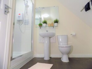 A bathroom with a glass shower enclosure, a pedestal sink, a toilet, and a mirror above the sink. - Casa Homestay (Coventry)