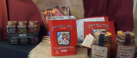 A display of MATIZ brand products including jars of pimentón dulce, a can of pimentón el angel, and a booklet.