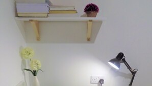 A white desk with a lamp, a small plant, and a shelf with books and a potted plant. - Muse Homestay (Coventry)
