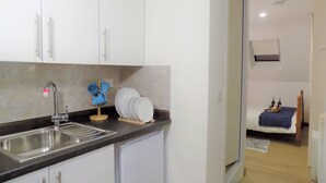 A compact kitchen with white cabinets, a stainless steel sink, and a blue mug rack. - Muse Homestay (Coventry)