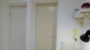 A room with a white door, a white wall, a small shelf with a potted plant, and a map. - Muse Homestay (Coventry)