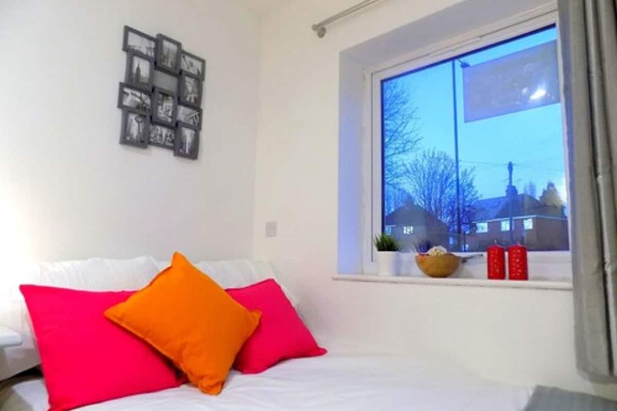 A bedroom with a bed, pillows, a window, and a wall-mounted picture frame.