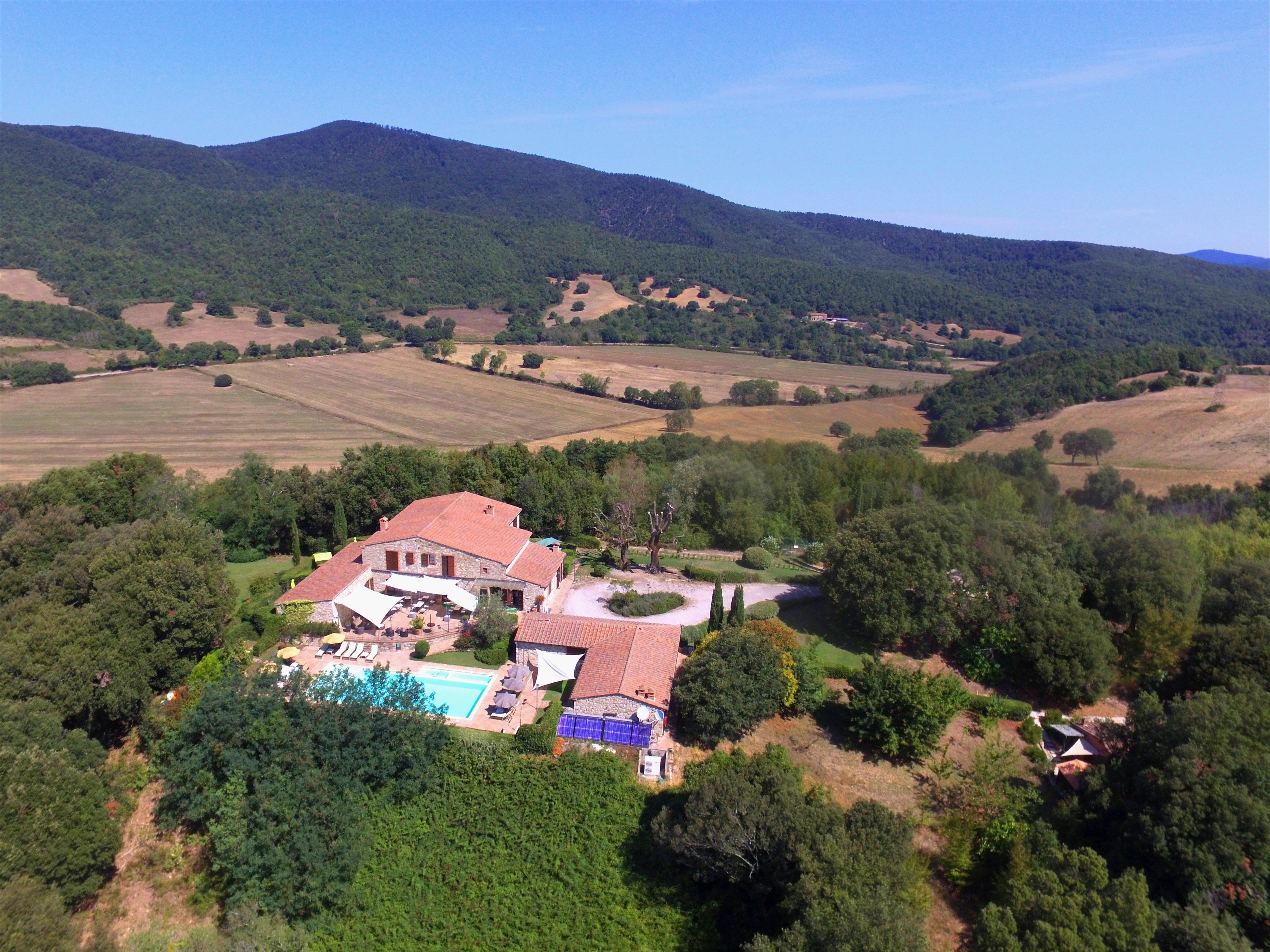 Un'ampia casa con piscina, immersa nel verde e circondata da campi.