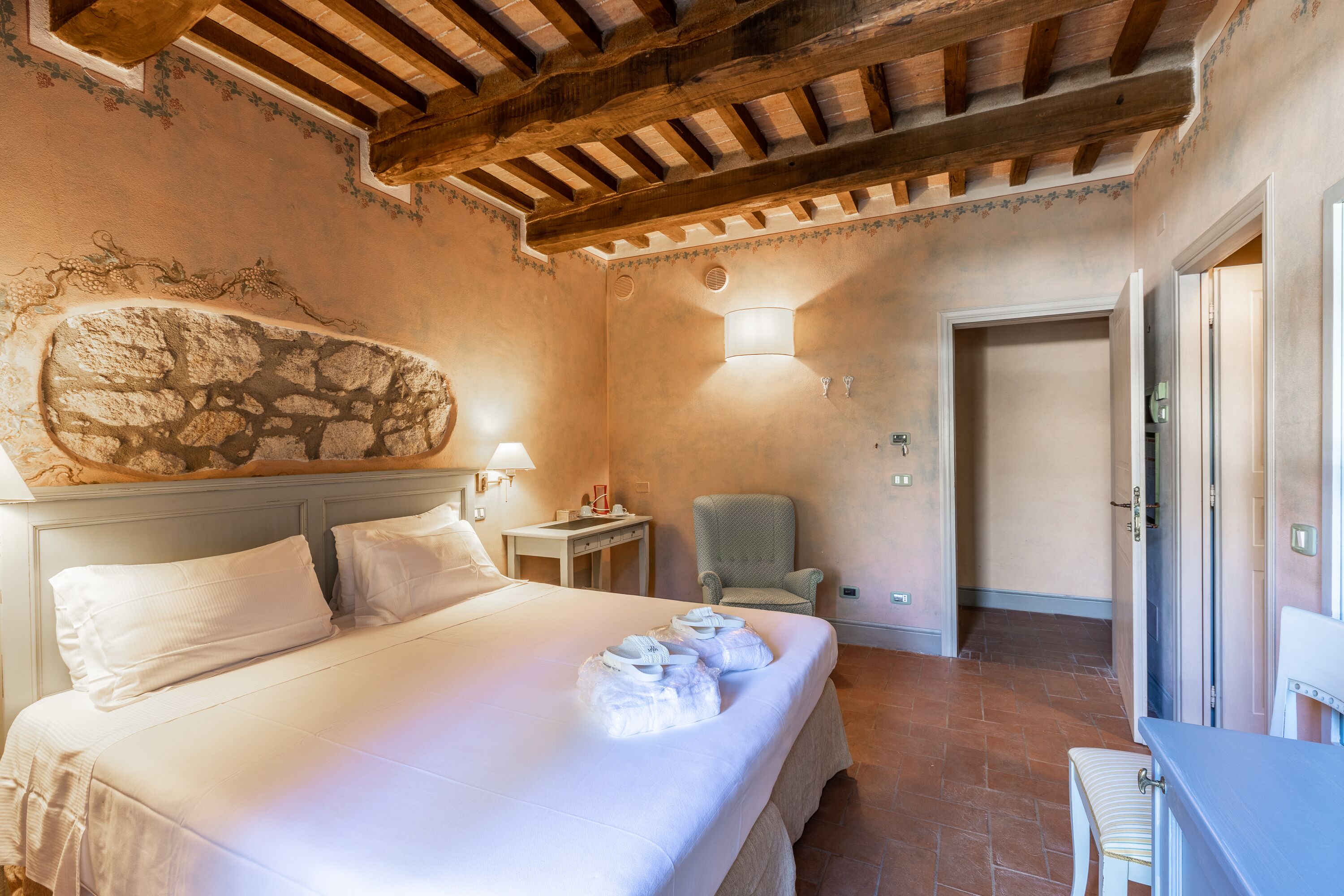 Une chambre d’hôtel avec un grand lit, un mur en pierre, une chaise et un bureau.