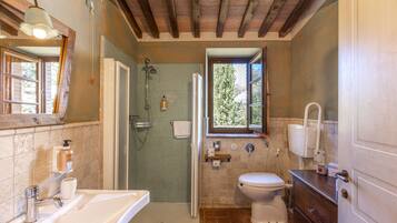 A bathroom with a shower, toilet, sink, and wooden cabinets.