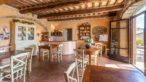 Un intérieur rustique avec des poutres apparentes, un îlot central doté de sièges et un mur en pierre.