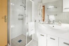 A modern bathroom with a glass-enclosed shower, a white sink with chrome fixtures, and a mirror above the sink. - Hotel Bellerofonte (Rimini)