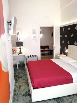 A hotel room with a bed, a desk, a chair, a trash bin, and a mirror. - B&B Abatjour (Foggia)