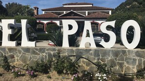En stor skylt med ordet ”EL PASO” framför en byggnad med ett tak täckt av tegelpannor och väggar av sten.