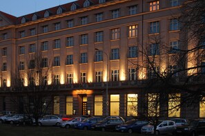 A multi-story hotel with a row of windows on the ground floor, a sign reading "HOTEL A P", and several parked cars in front. - Hotel DAP (Prague)