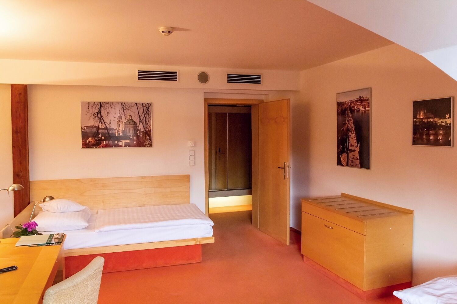 Une chambre d’hôtel avec un lit, une table de chevet, une lampe et une armoire en bois.