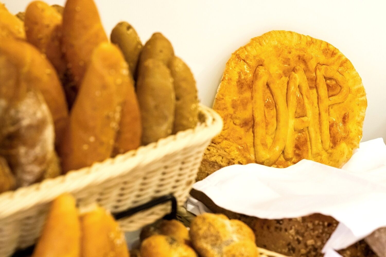 A basket of breadsticks and a round bread with a pattern.