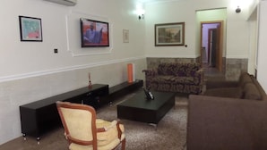 Ein Wohnzimmer mit Fernseher, einer Couch, einem Sessel und einem Couchtisch.