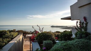 A coastal view with a concrete pathway leading to a building with a balcony overlooking the sea. - Marathon Blue (Marathon)