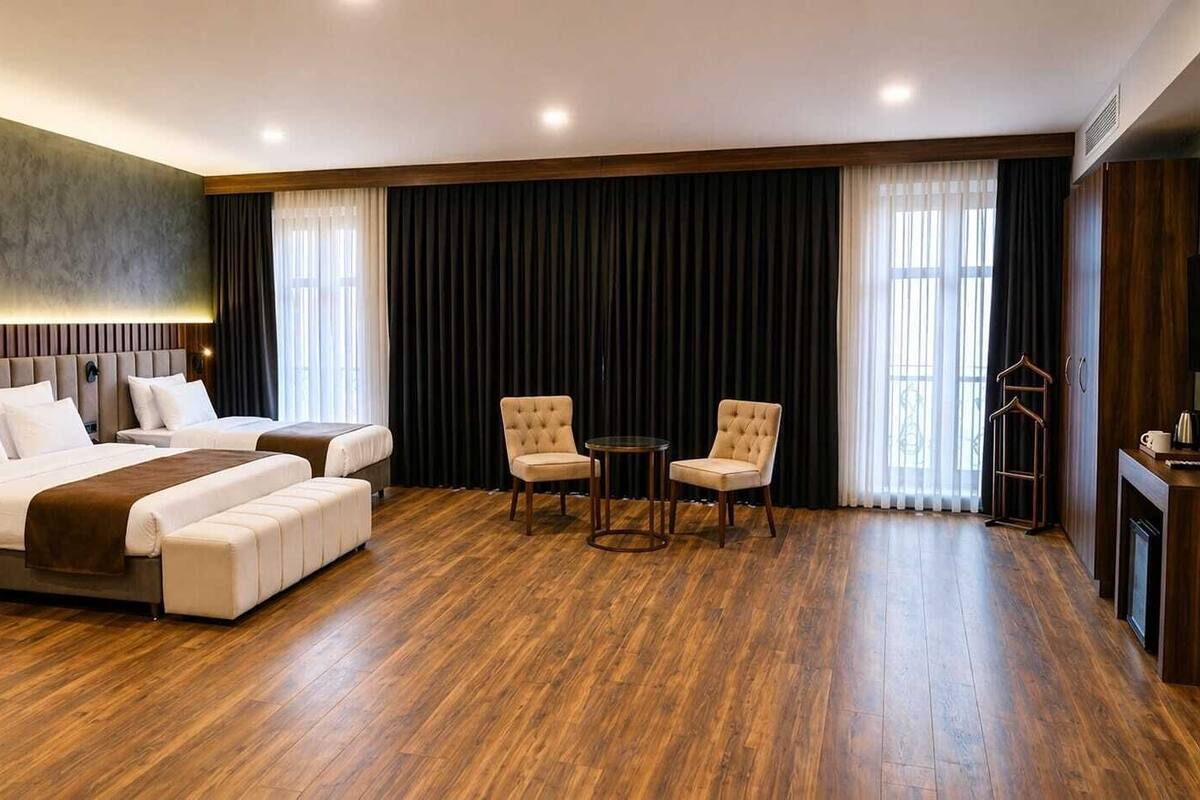 A hotel room with a large bed, two armchairs, a small table, and a television.