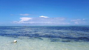 A clear view of a calm sea with a boat in the distance and a buoy on the shore. - Tamani Villas (Matemwe)