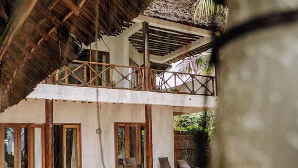 A pool area with lounge chairs and a thatched roof structure. - Tamani Villas (Matemwe)