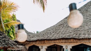 A resort with thatched-roof buildings, stone flooring, and wicker lounge chairs. - Tamani Villas (Matemwe)