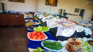 A buffet table with various food items and a kitchen area in the background. - Can Grand Hotel  (Ankara)
