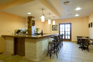 A kitchen area with a brick counter, bar stools, and a coffee machine.